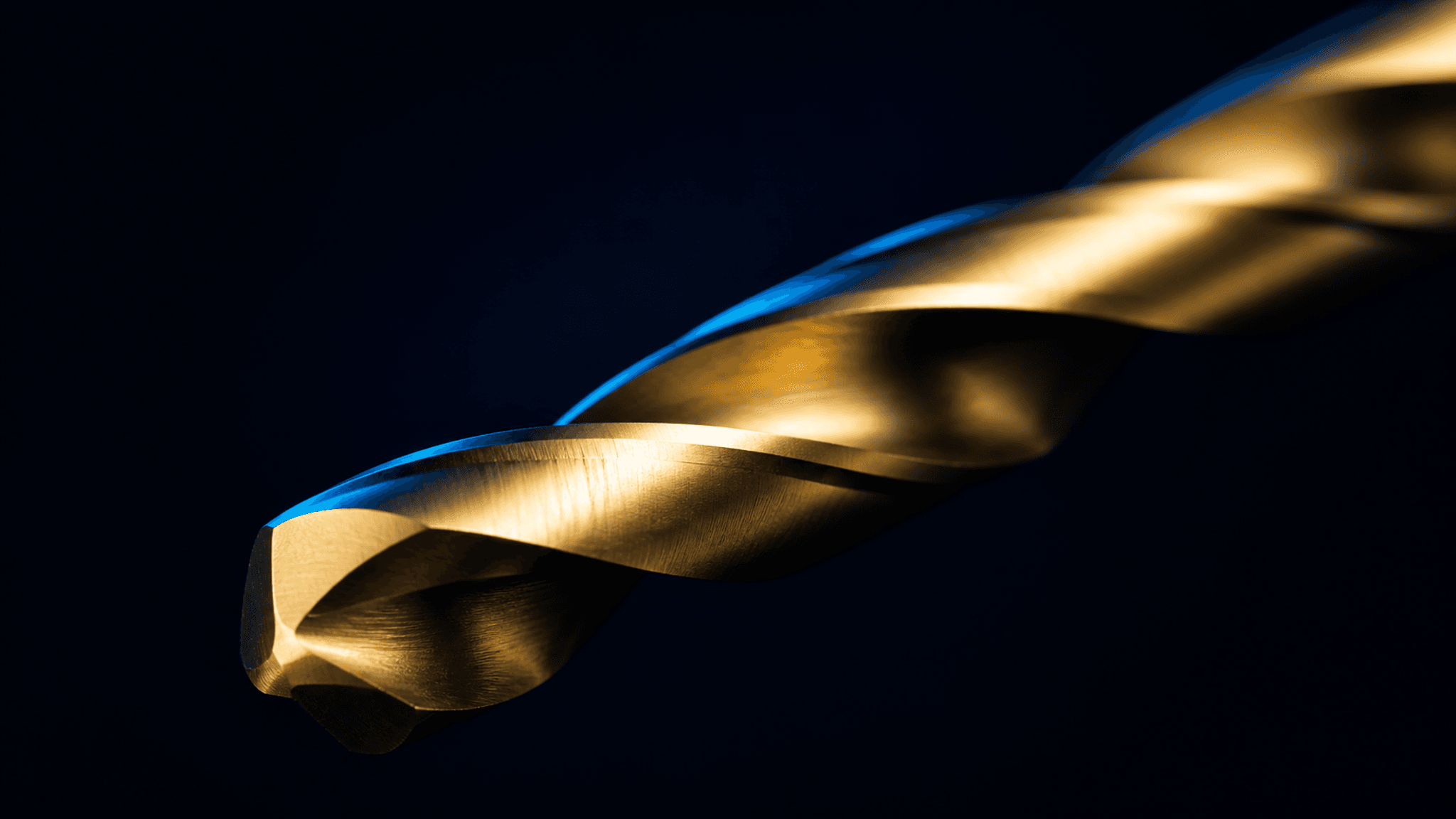 Macro view of gold-toned surgical drill flutes against a deep navy field