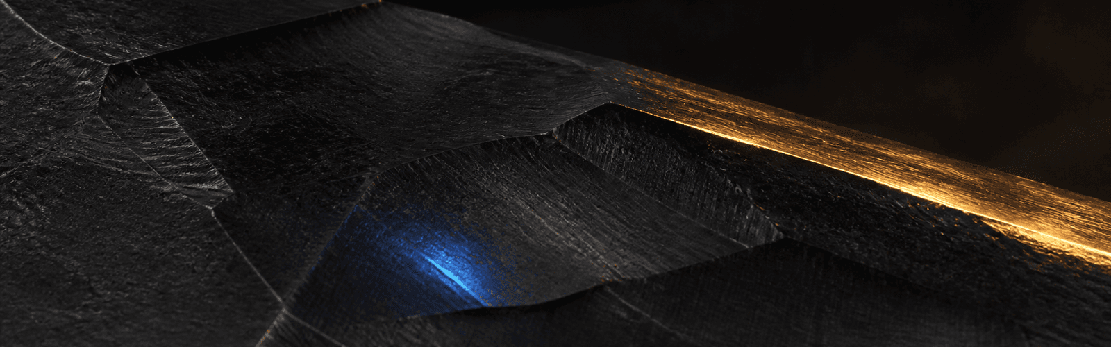 Machined dark metal with a gold cutting edge and blue highlight